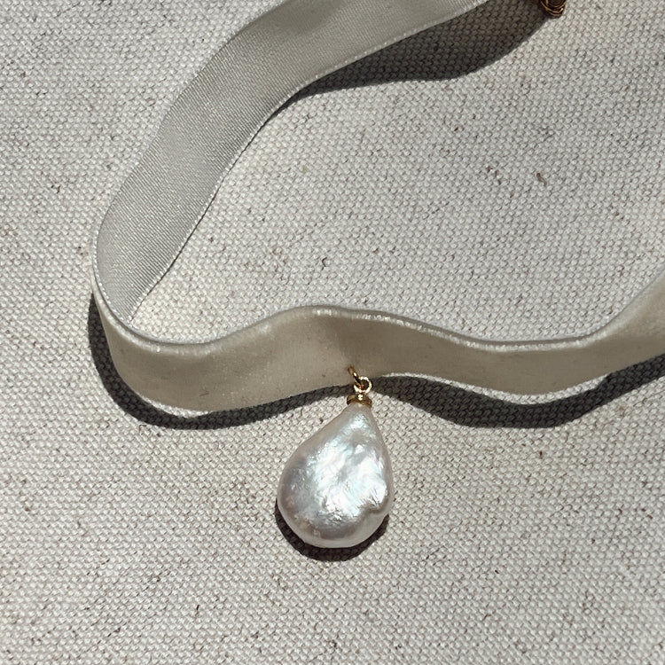 Pearl necklace with a gold clasp on a textured fabric background