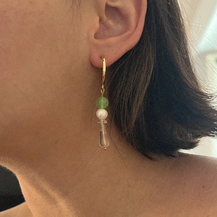 Close-up of an earring with green and clear beads worn by a person.