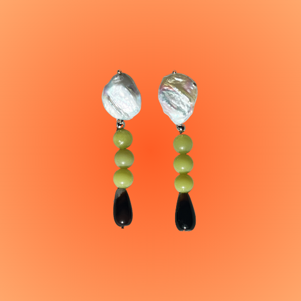 Pair of earrings with green beads and black accents on an orange background