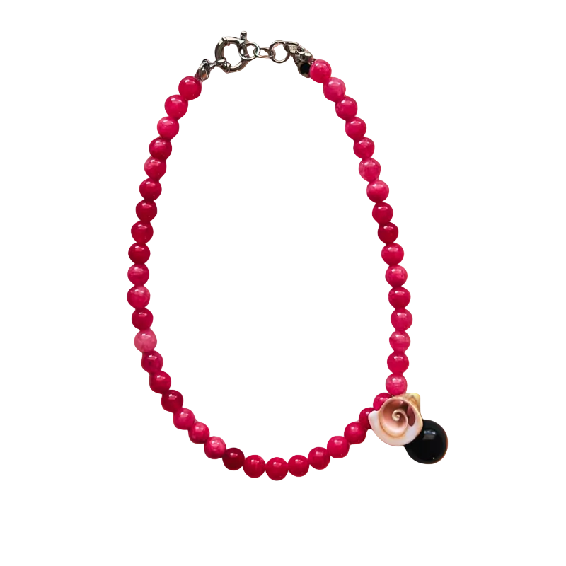 Pink beaded bracelet with a black and gold charm on an orange gradient background