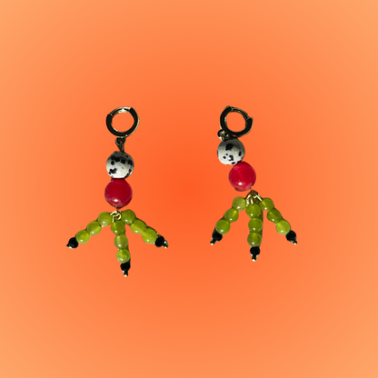 Pair of earrings with cartoon character figures on an orange gradient background