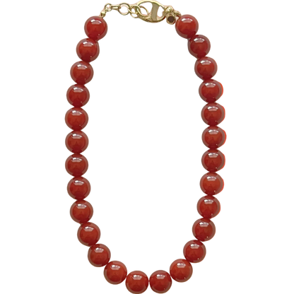 Red beaded necklace with a gold clasp on an orange gradient background