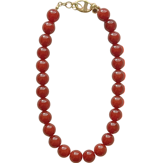 Red beaded necklace with a gold clasp on an orange gradient background
