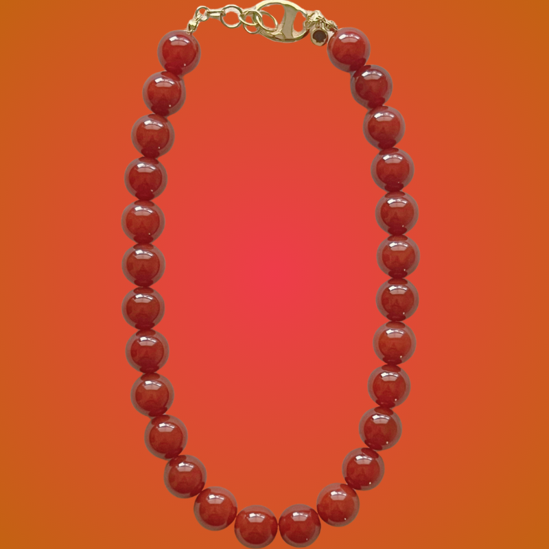 Red beaded necklace with a gold clasp on an orange gradient background