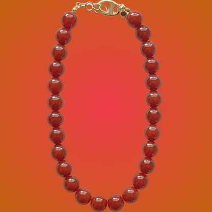 Red beaded necklace with a gold clasp on an orange gradient background