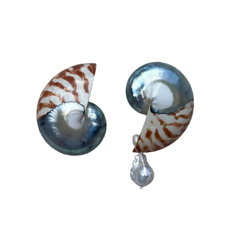 A pair of earrings made from spiral nautilus shells with iridescent blue-gray and brown patterns, each hanging from a small white pearl drop, displayed on a textured beige fabric background.