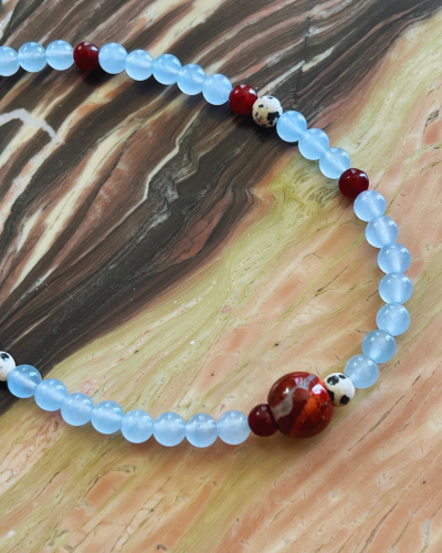 Beaded necklace with blue, red, and white beads on a marbled surface