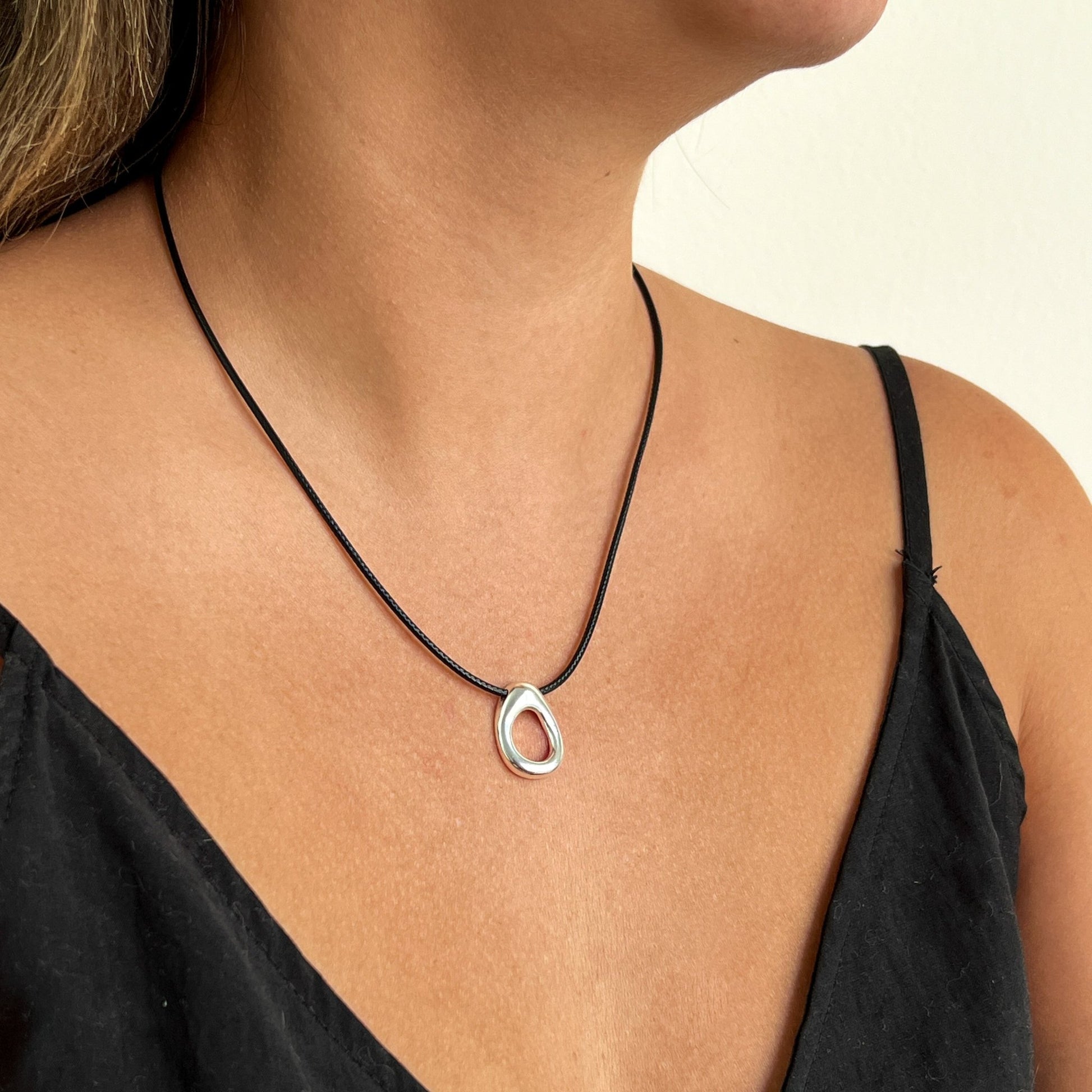 Simple circular leather necklace with a small organically shaped circular sterling silver pendant.