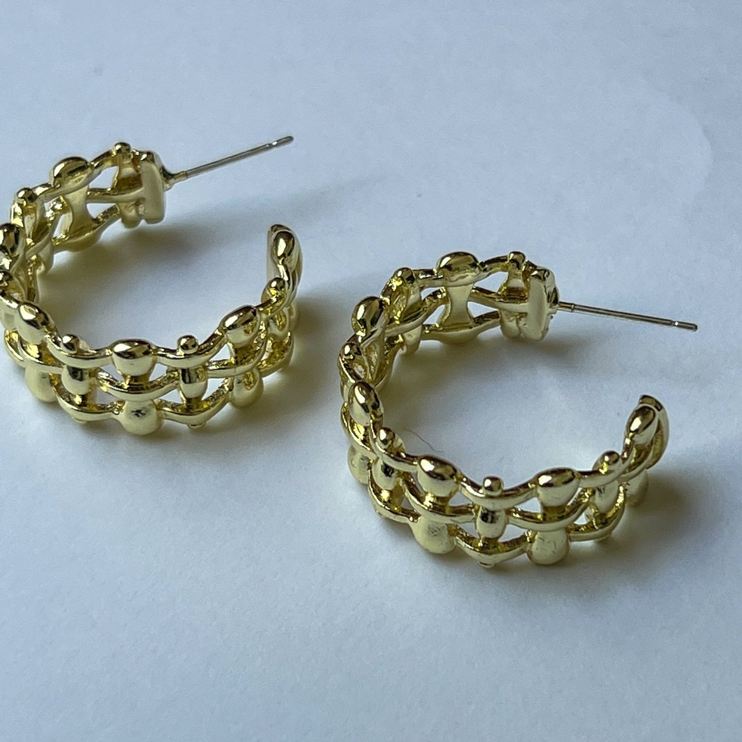 Gold lattice textured design of half open hoop earrings.