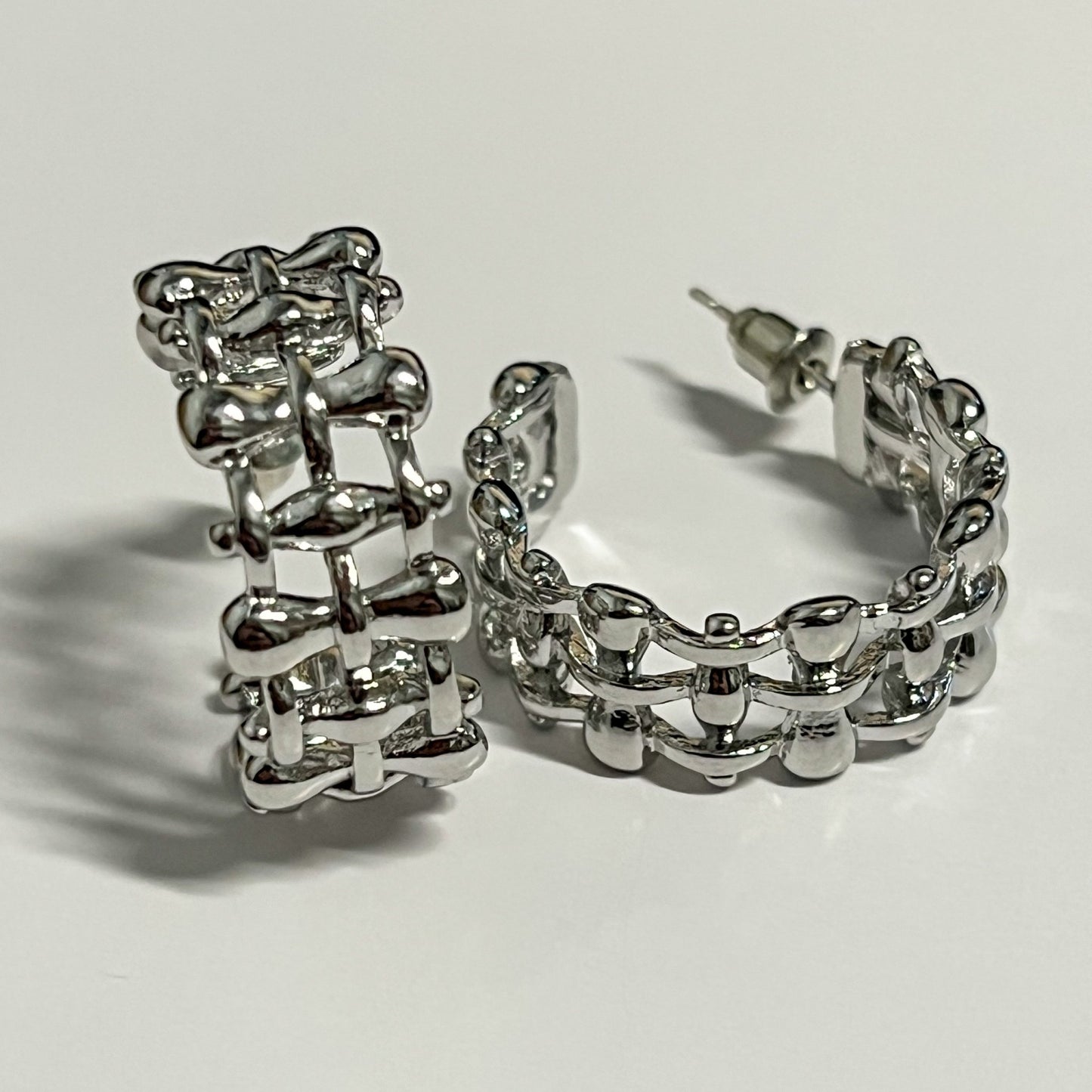 Silver lattice textured design of half open hoop earrings.